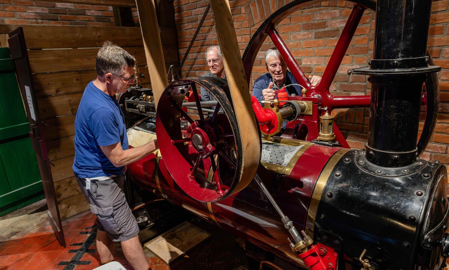 3 men servicing a vintage engine