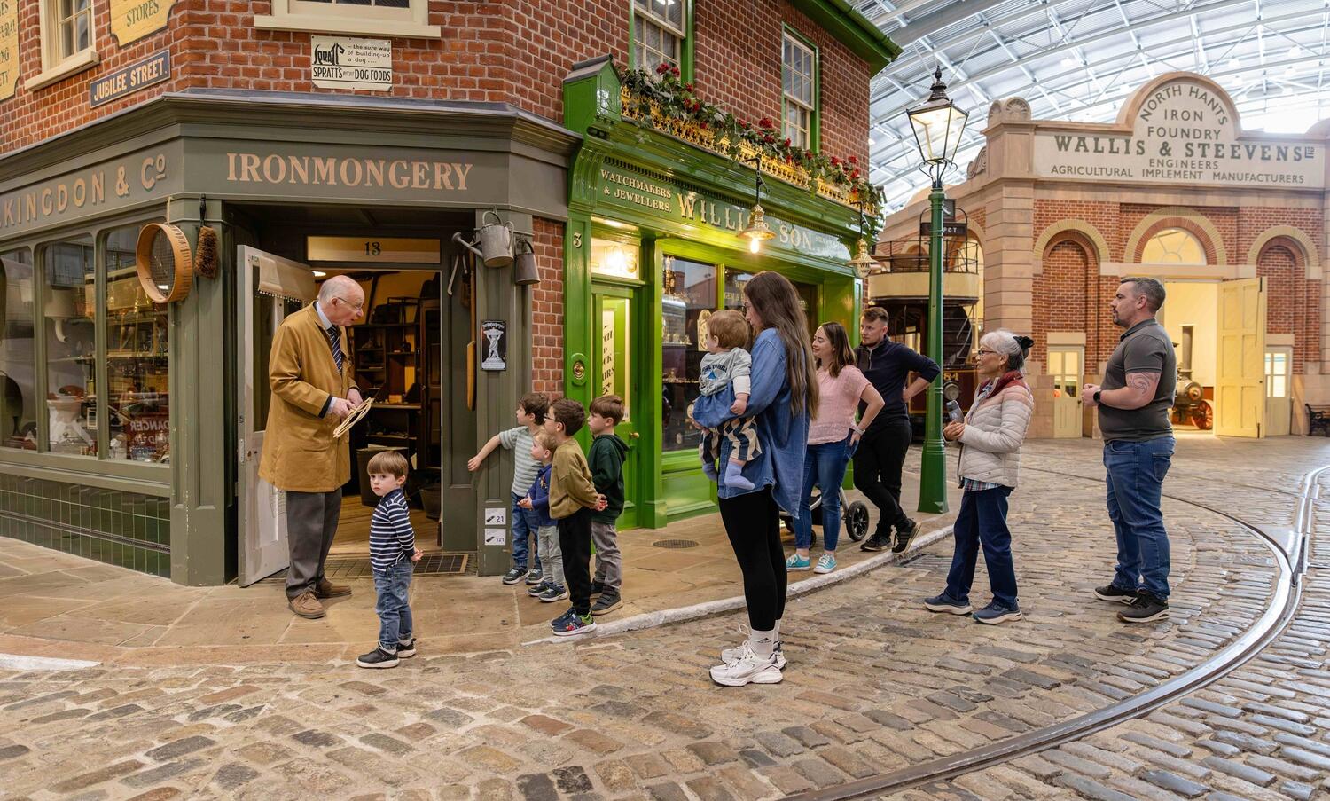Street scene with family talking to costumed character outside the Ironmongery