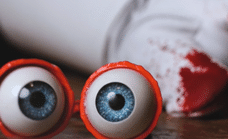A pair of eyes with a bloody glove in the background