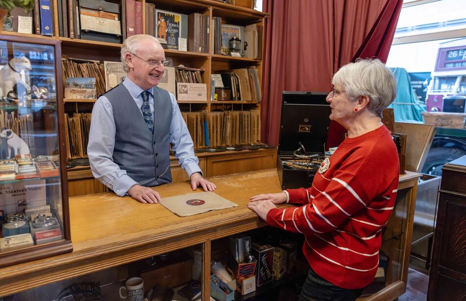 Female visitor in our record shop chatting to one of our costumed volunteers