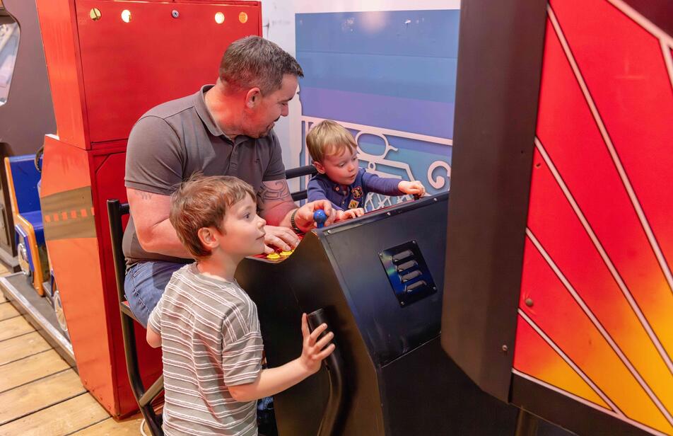 Dad playing with sons on retro arcade machines