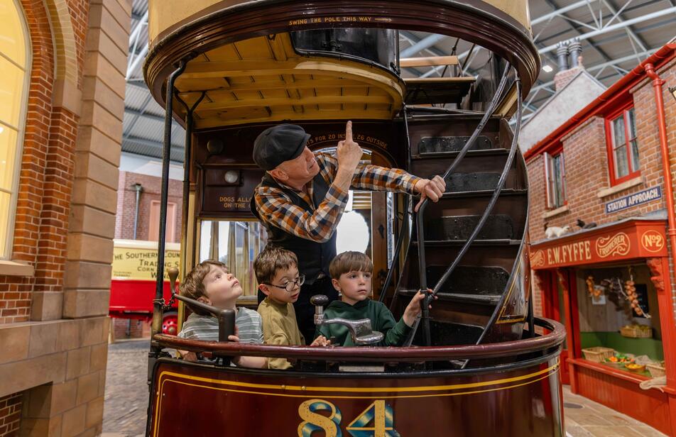 A person and three children inside a cart pointing up the stairs