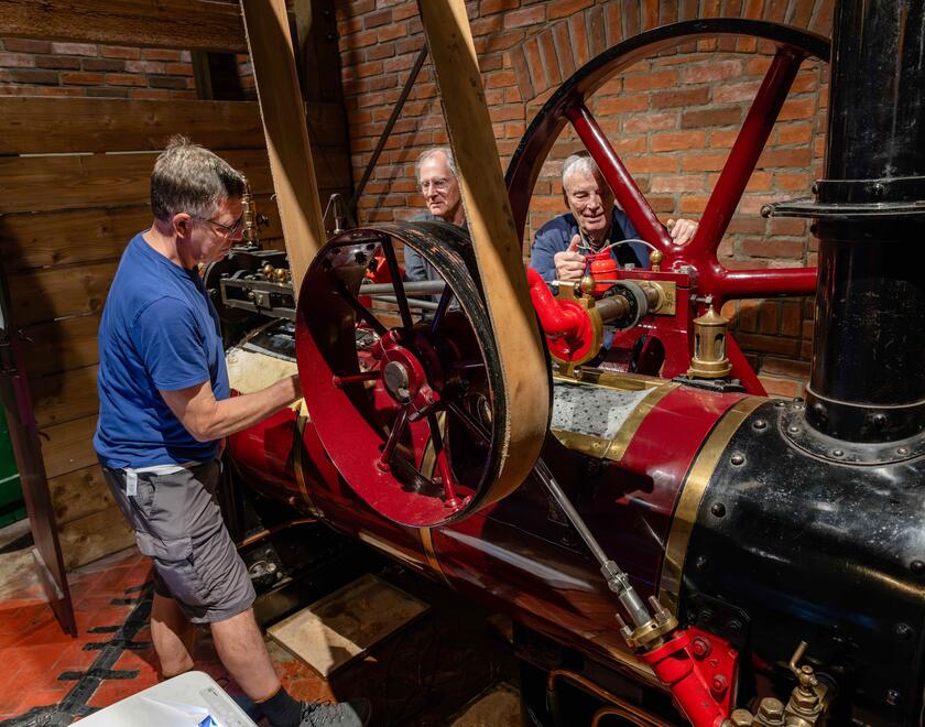 3 men servicing a vintage engine